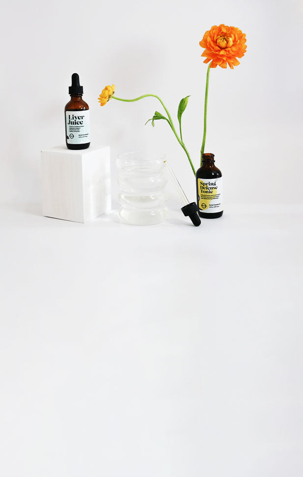 Front view of Spring Relief Duo: two amber 2 fl oz droppers (Liver Juice, Spring Defense Tonic) with orange flowers on white