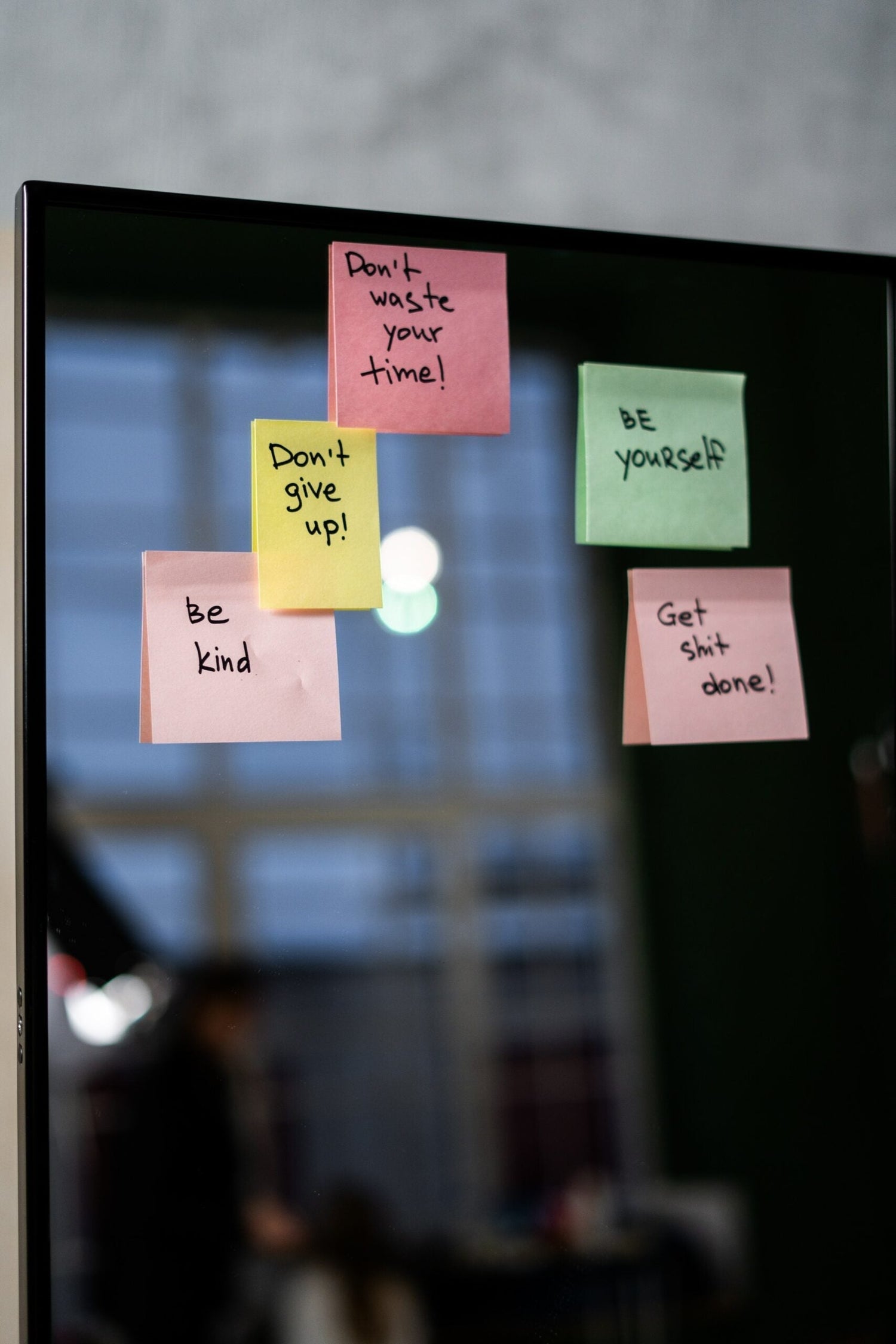 Mirror with colorful sticky notes reading Don’t waste your time, Don’t give up, Be kind, Be yourself, and Get shit done against a blurred room