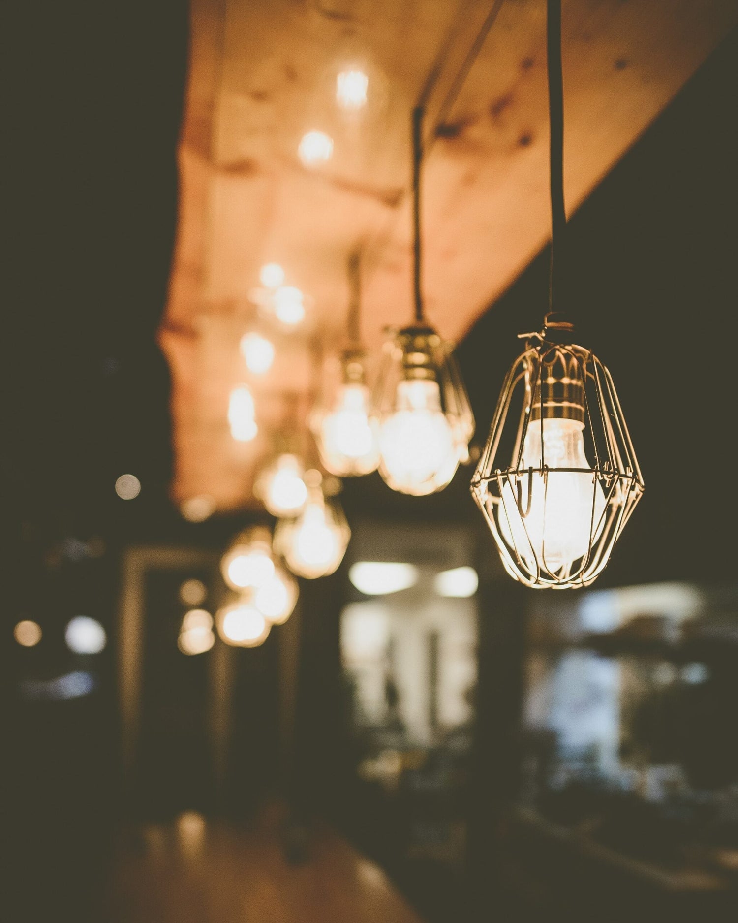 Row of hanging filament light bulbs glowing in a dim, warm-toned interior