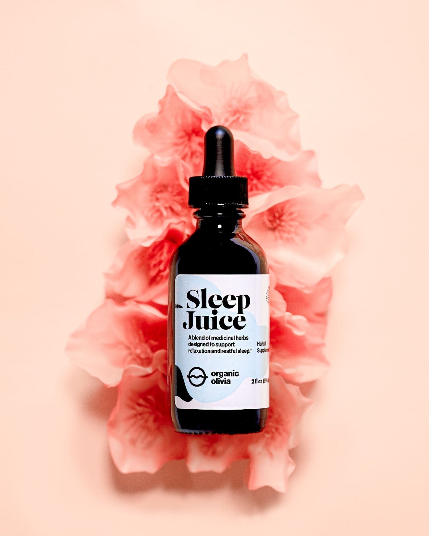 Front view of Sleep Juice dropper bottle showcasing the label text and black dropper cap with a soft pink floral background