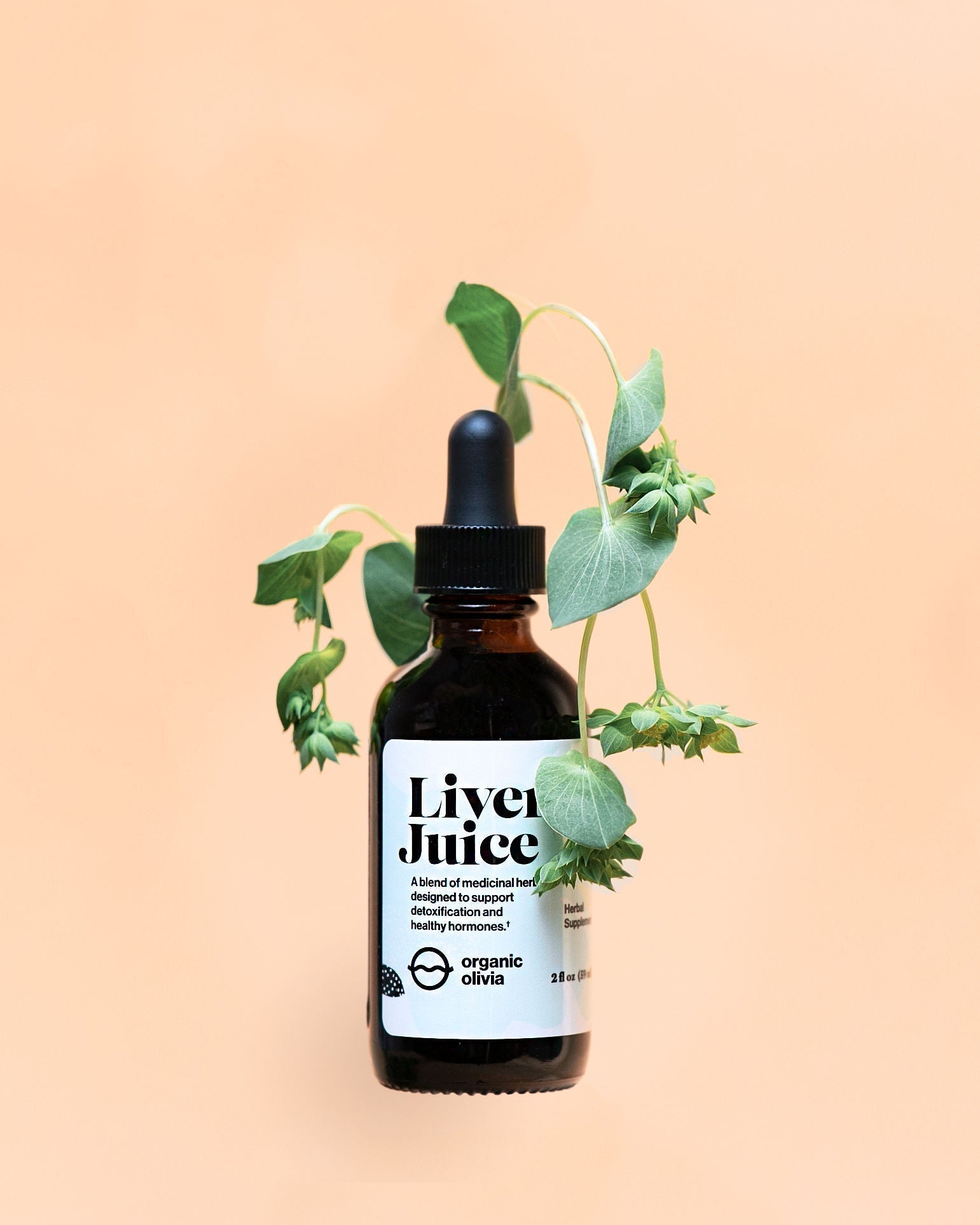 Front view of Liver Juice amber dropper bottle showcasing white label and trailing green leaves against a peach background