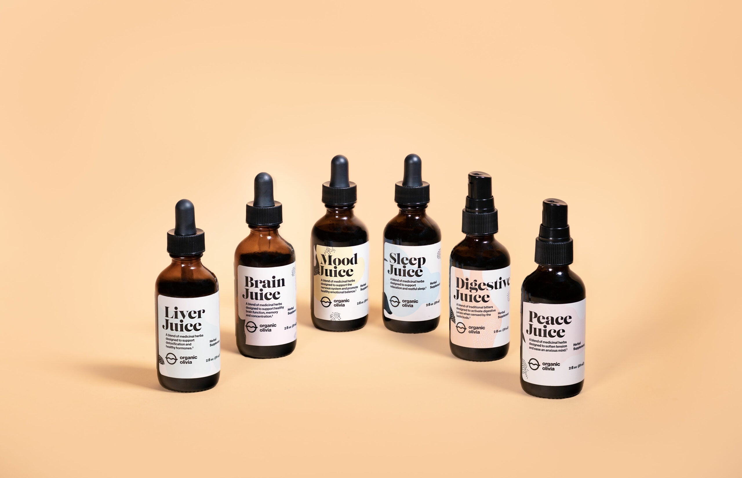 Front view of six amber tincture bottles labeled Liver Juice, Brain Juice, Mood Juice, Sleep Juice, Digestive Juice and Peace Juice on a peach background
