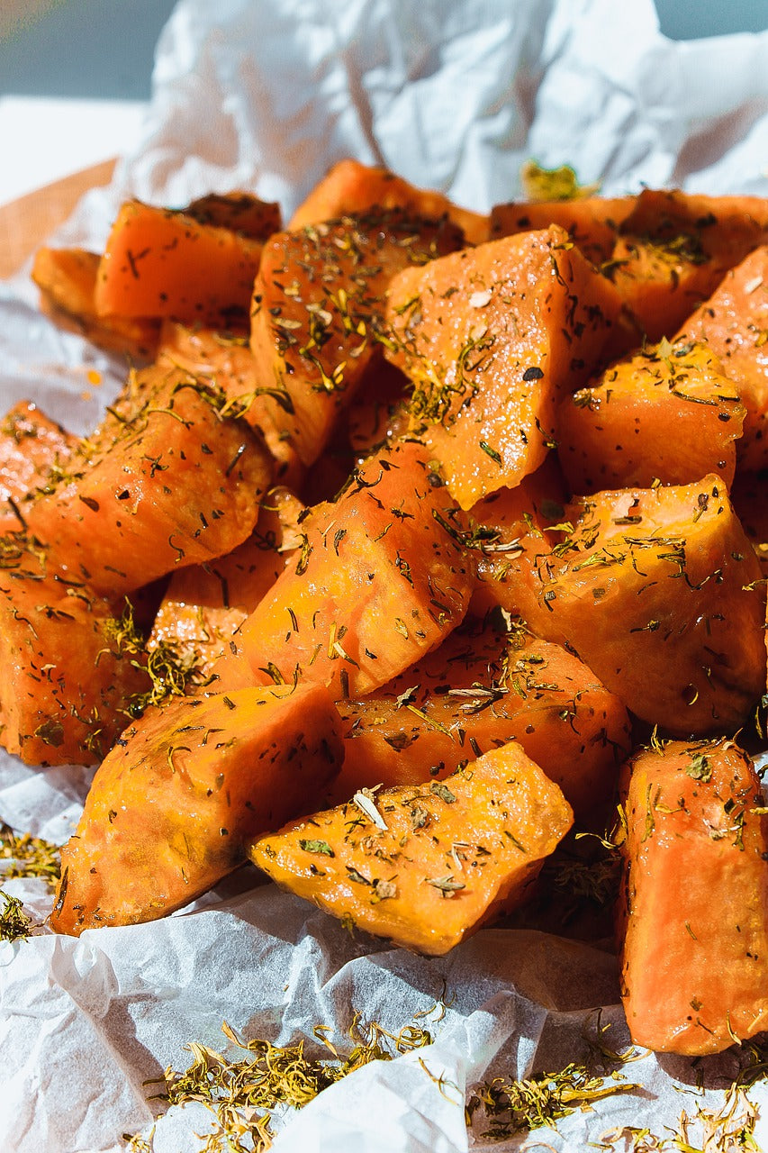 Roasted sweet potato chunks seasoned with herbs on crumpled parchment paper