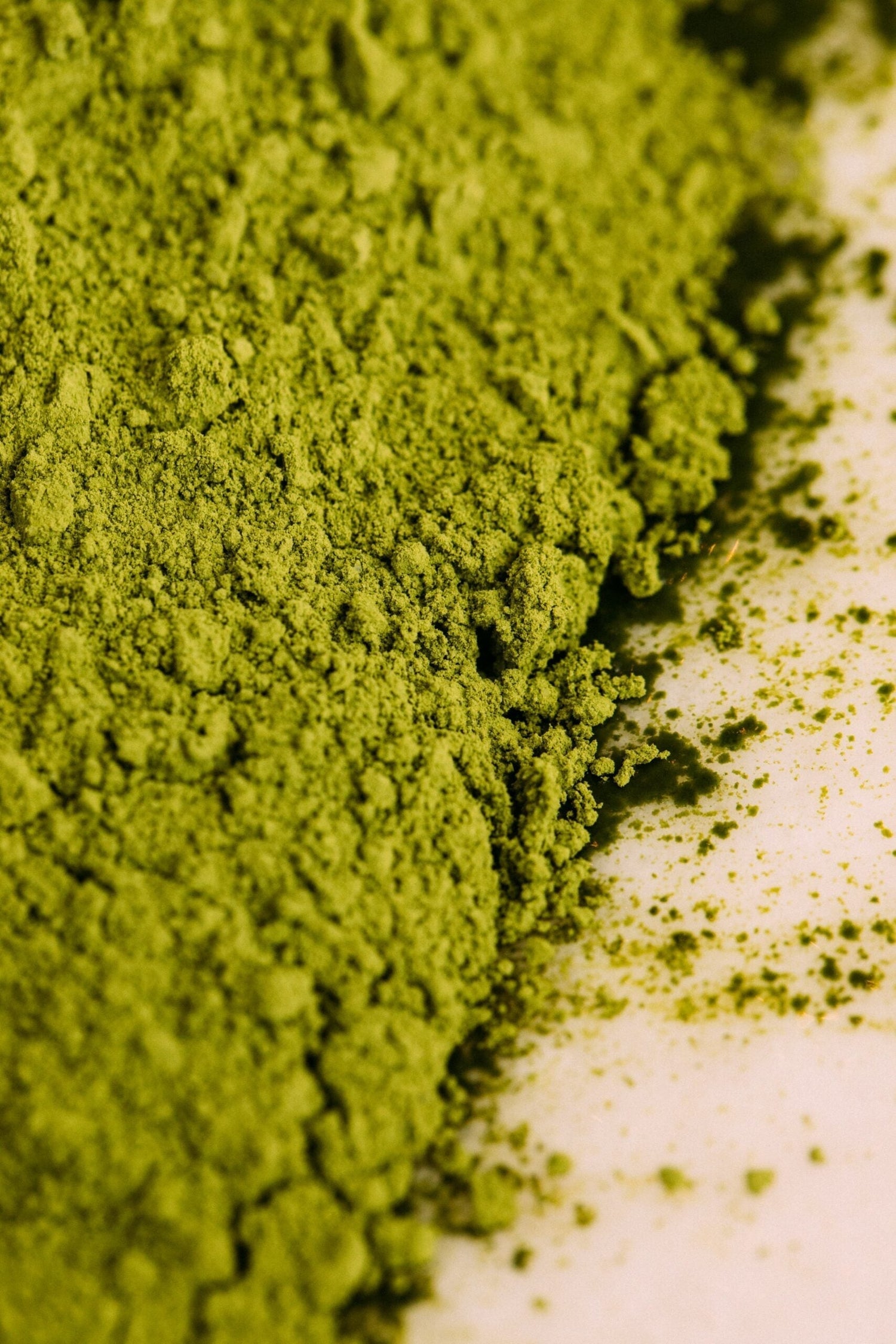 Close-up of matcha green tea powder showing its fine bright green texture on a white surface