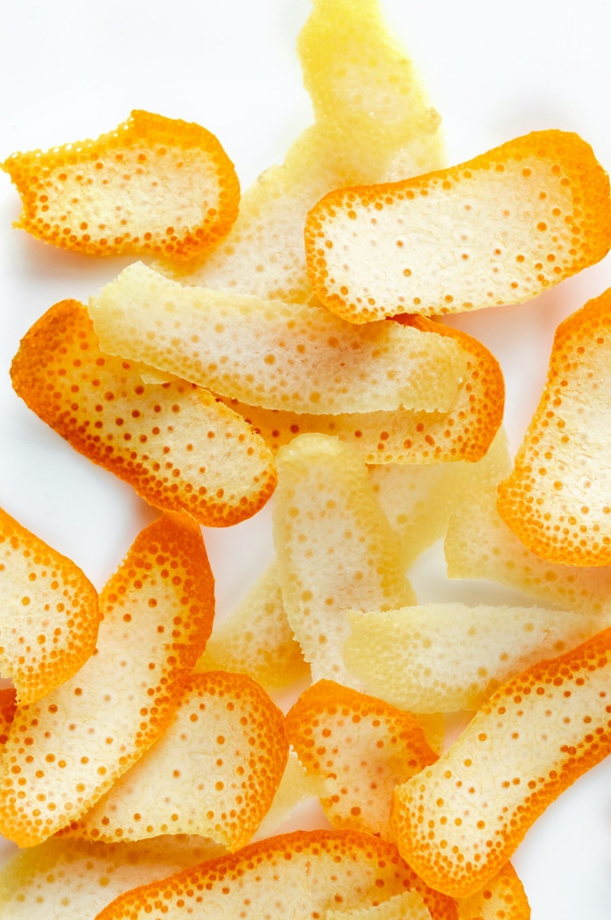 Overhead view of orange peels scattered on a white background