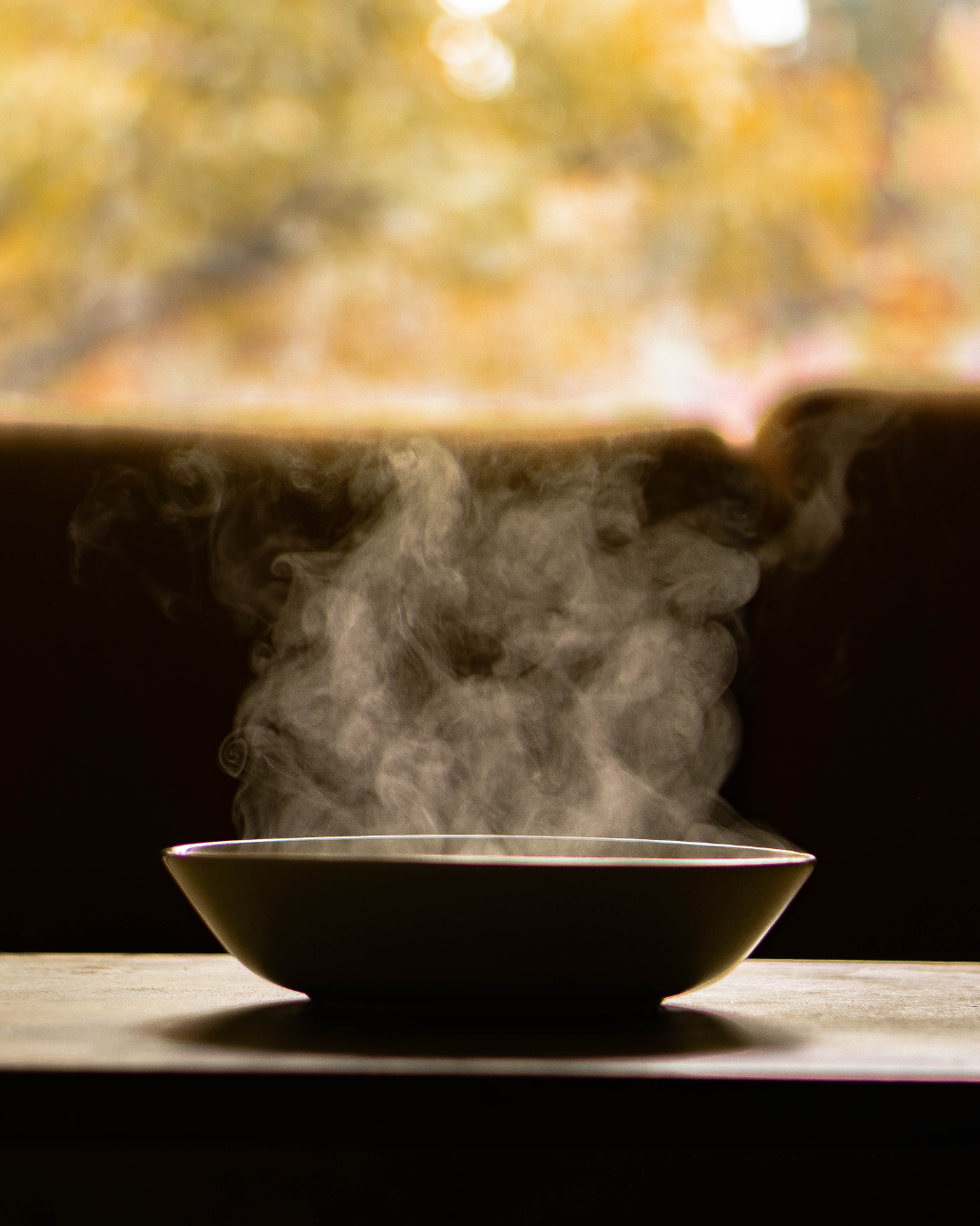 Bowl releasing steam on a table in front of a sunlit window