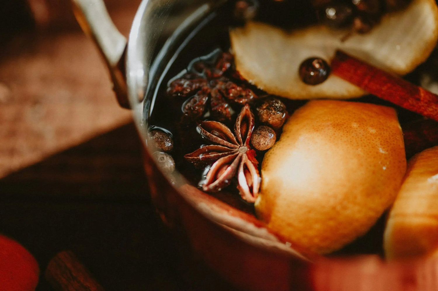 Simmer pot of pear slices, star anise, whole peppercorns and cinnamon sticks in a copper pot, warm autumn mood