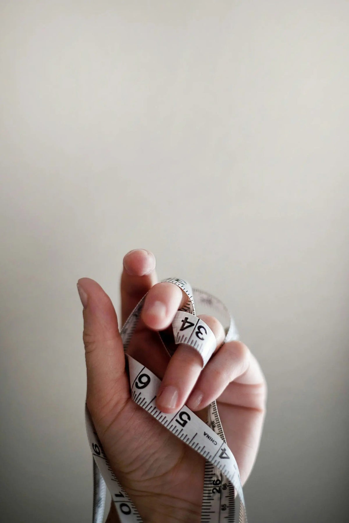 Hand holding a measuring tape, illustrating body measurements and metabolic health