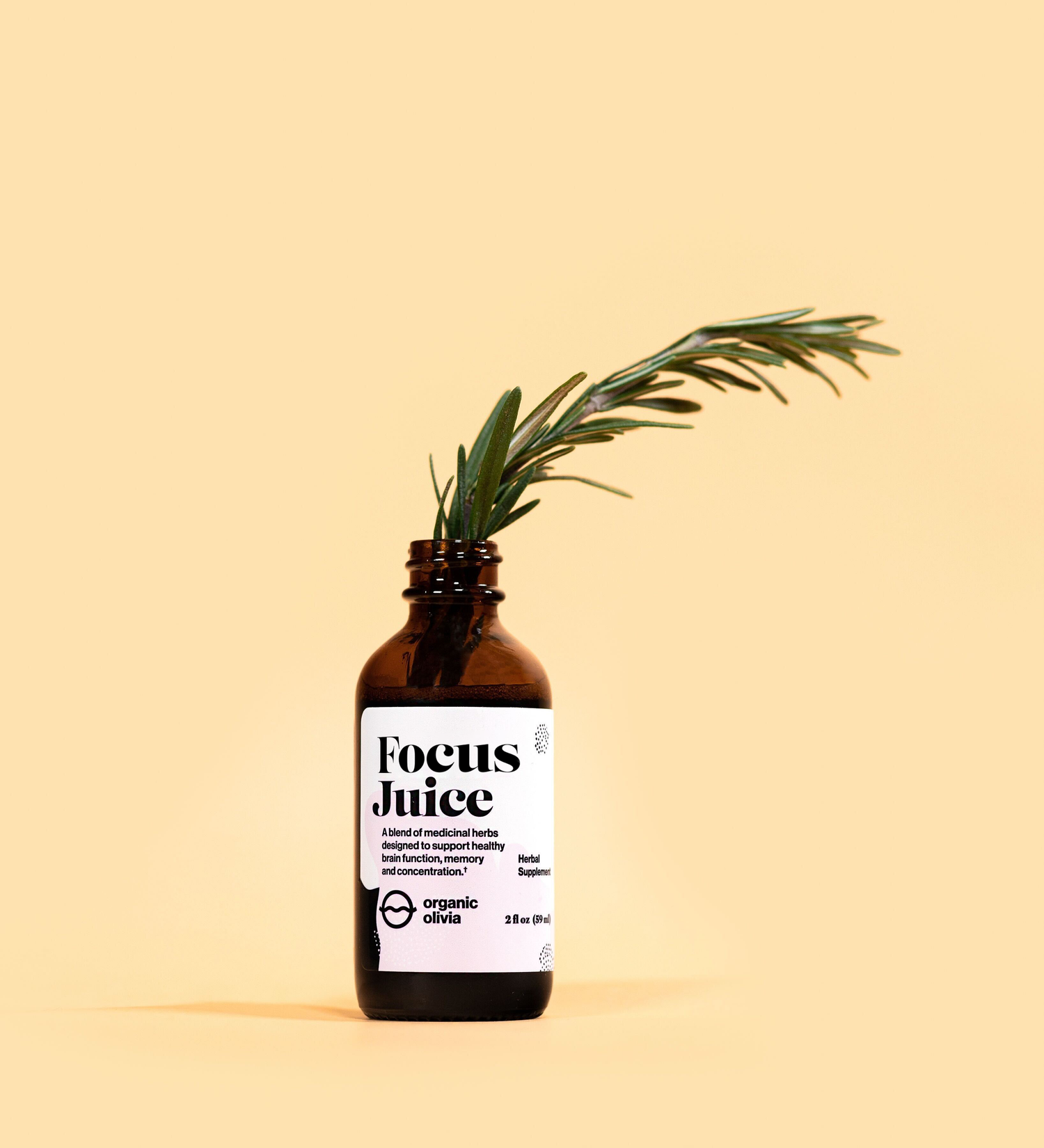 Front view of amber glass Focus Juice tincture bottle with white label and rosemary sprig on peach background