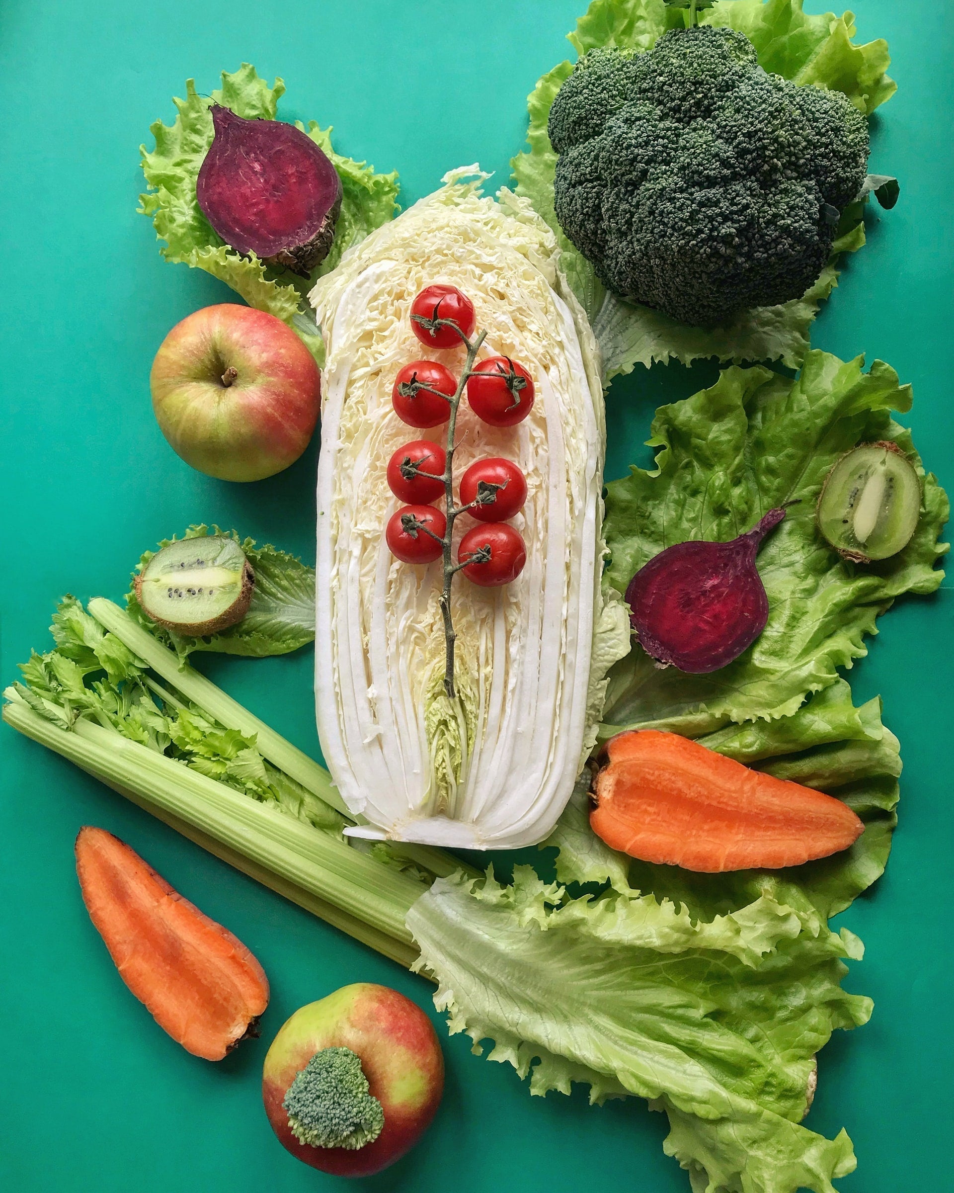 Flat lay of colorful fruits and vegetables on a teal background illustrating microbiome-friendly, gut-healthy foods