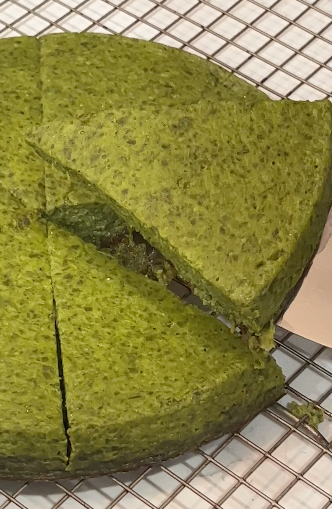 Angled close-up of a high-protein spinach frittata showing its green, airy texture and sliced wedges on a wire cooling rack