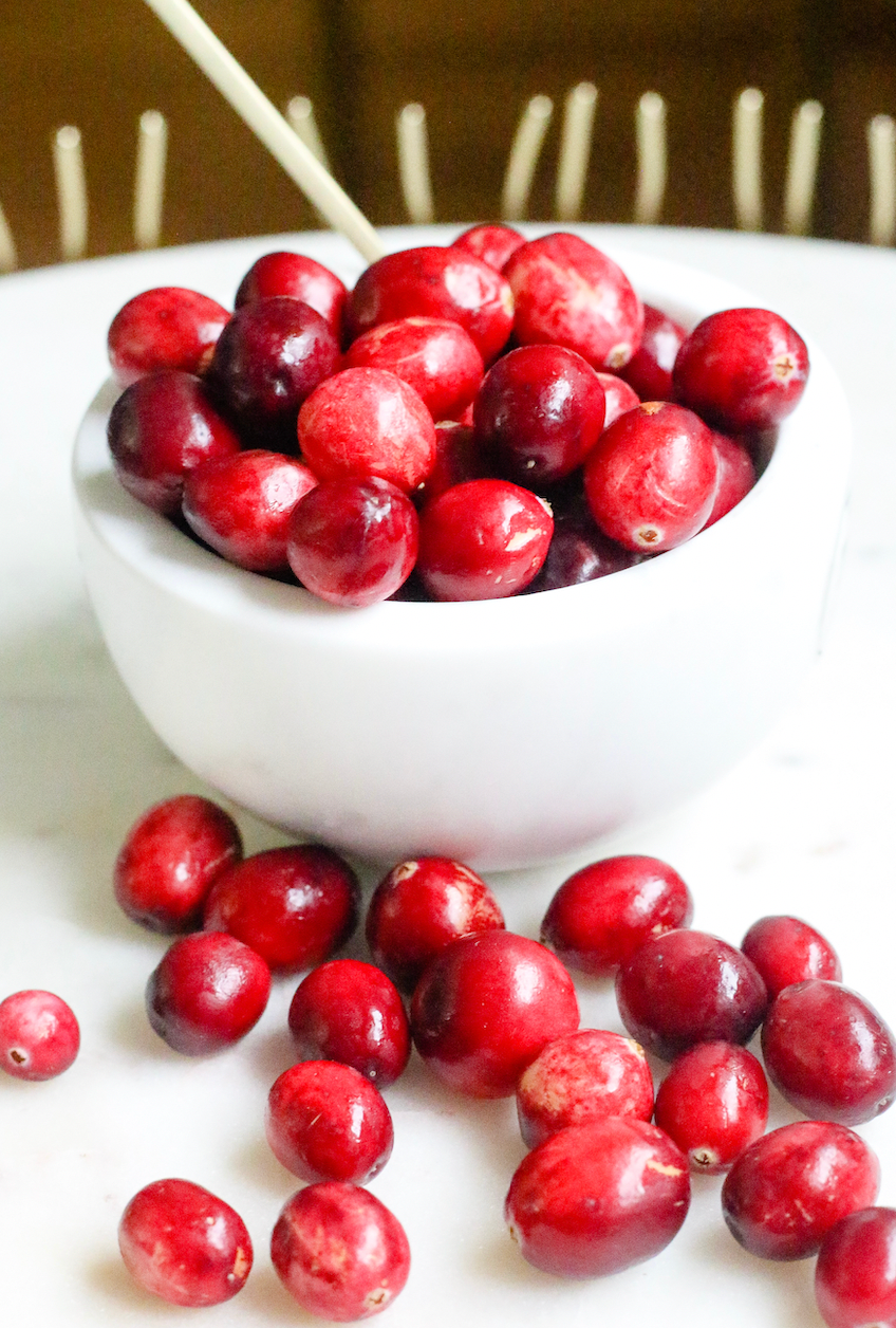 Bowl of fresh cranberries on a white marble surface