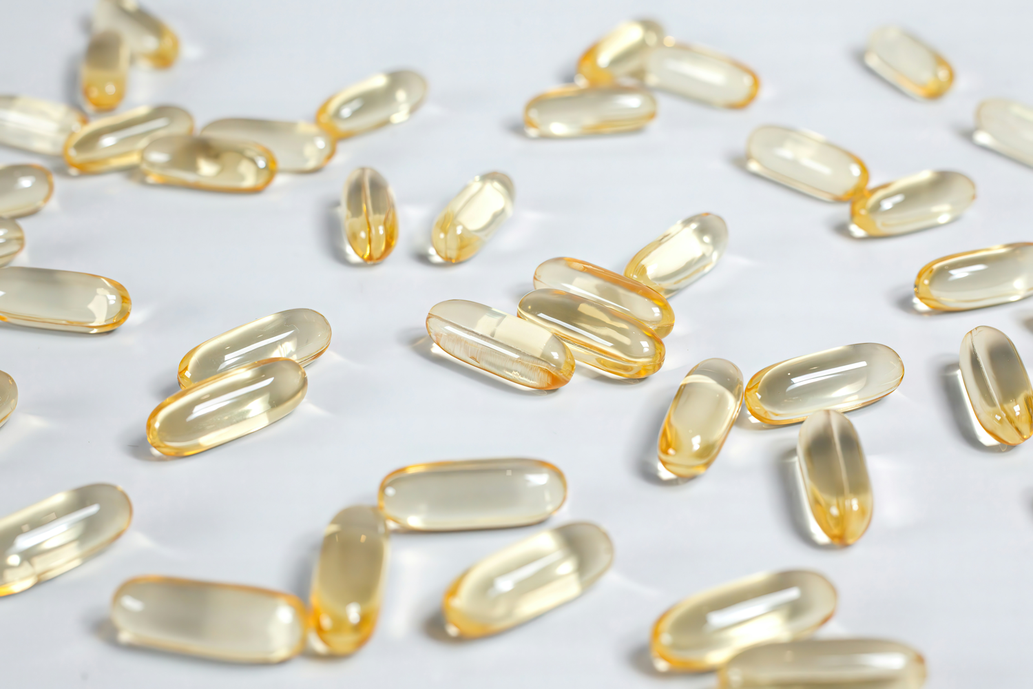 Top-down view of omega-3 softgel capsules showcasing translucent golden gel texture on a white background
