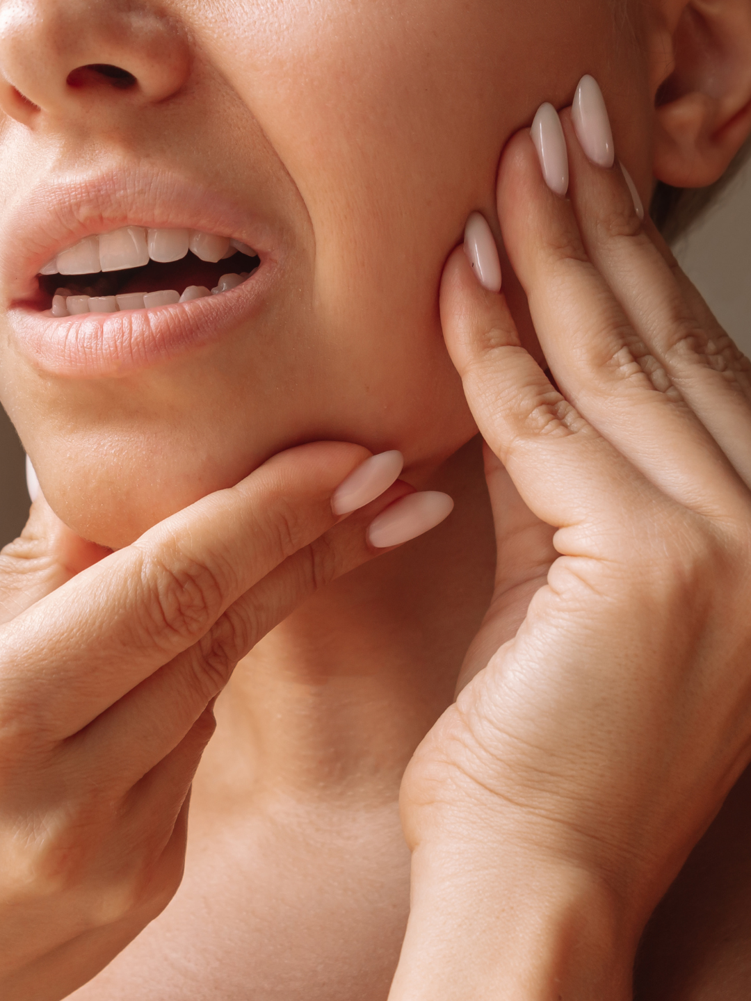 Close-up of a woman pressing her jaw and temple, showing jaw clenching and discomfort