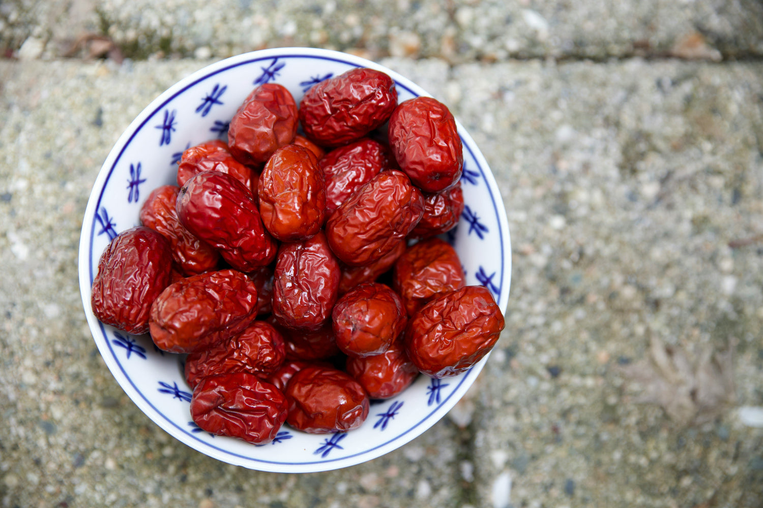 Bowl of dried red jujubes (Chinese red dates) on a stone surface
