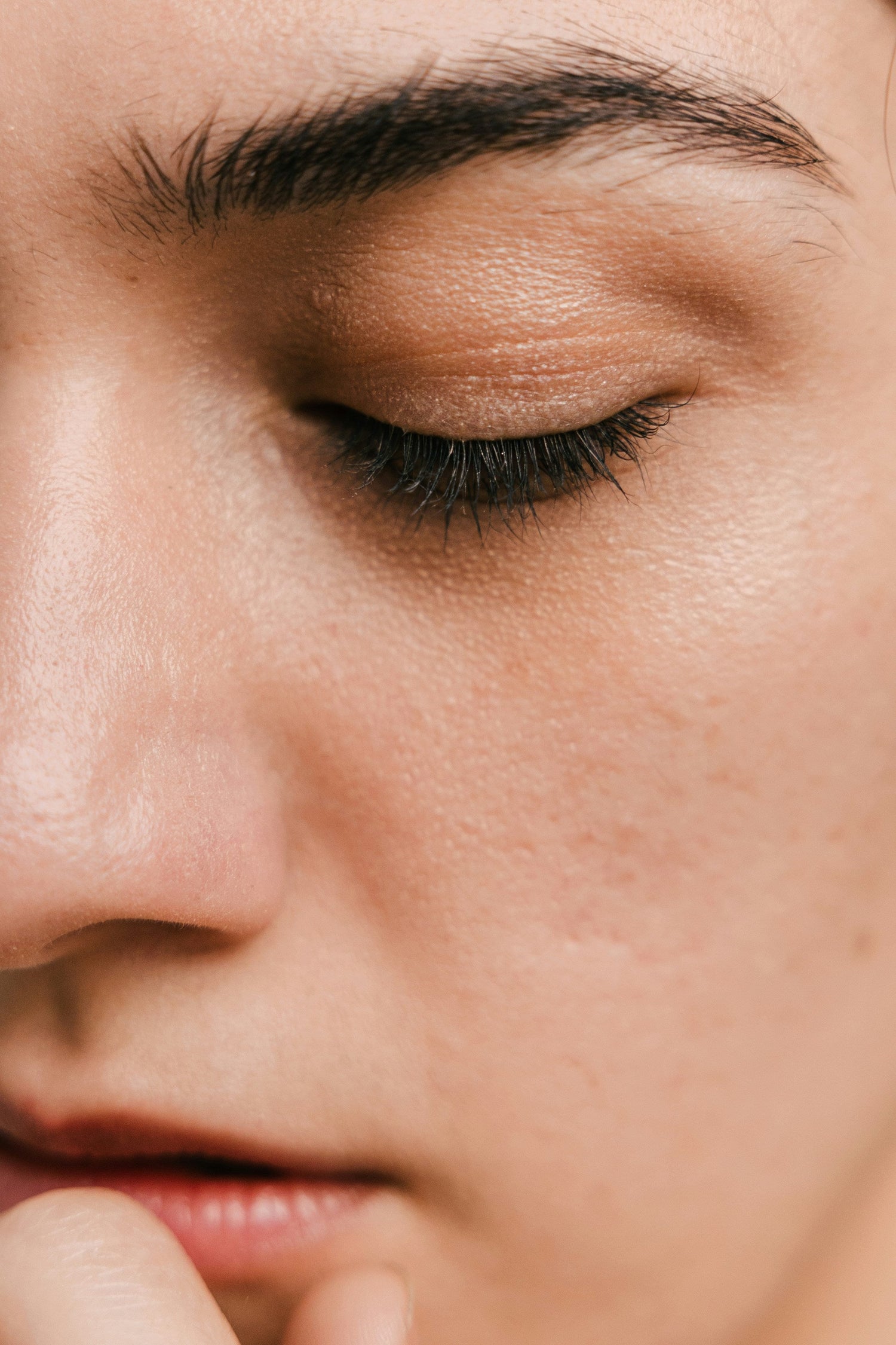 Close-up of a person’s cheek and closed eye showing skin texture, pores, and lashes