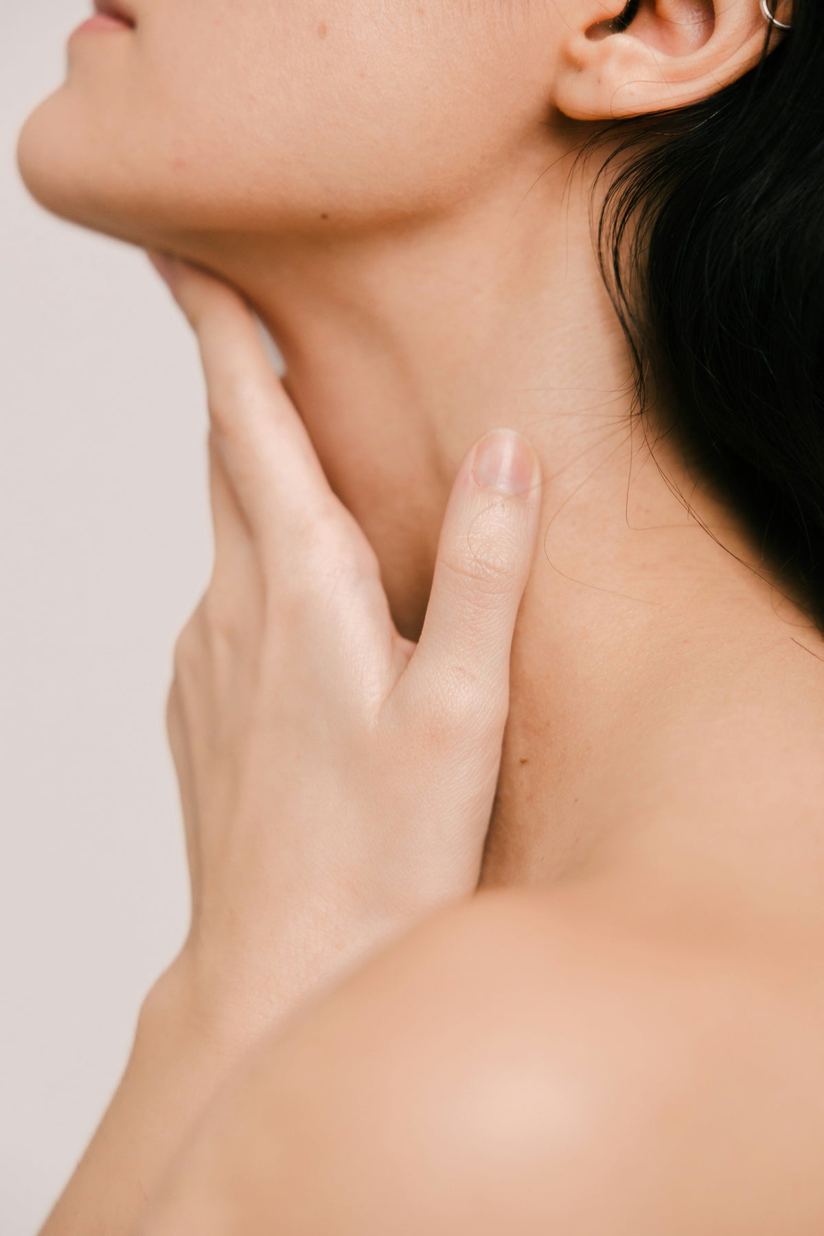 Person touching the skin along their jaw and neck in a close-up skincare image